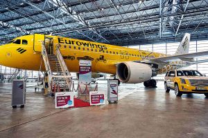 Gelbes Flugzeug von Eurowings fliegt mit Hertz