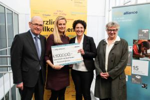 Help Alliance hilft mit Spenden-Scheck für Flüchtlinge in München